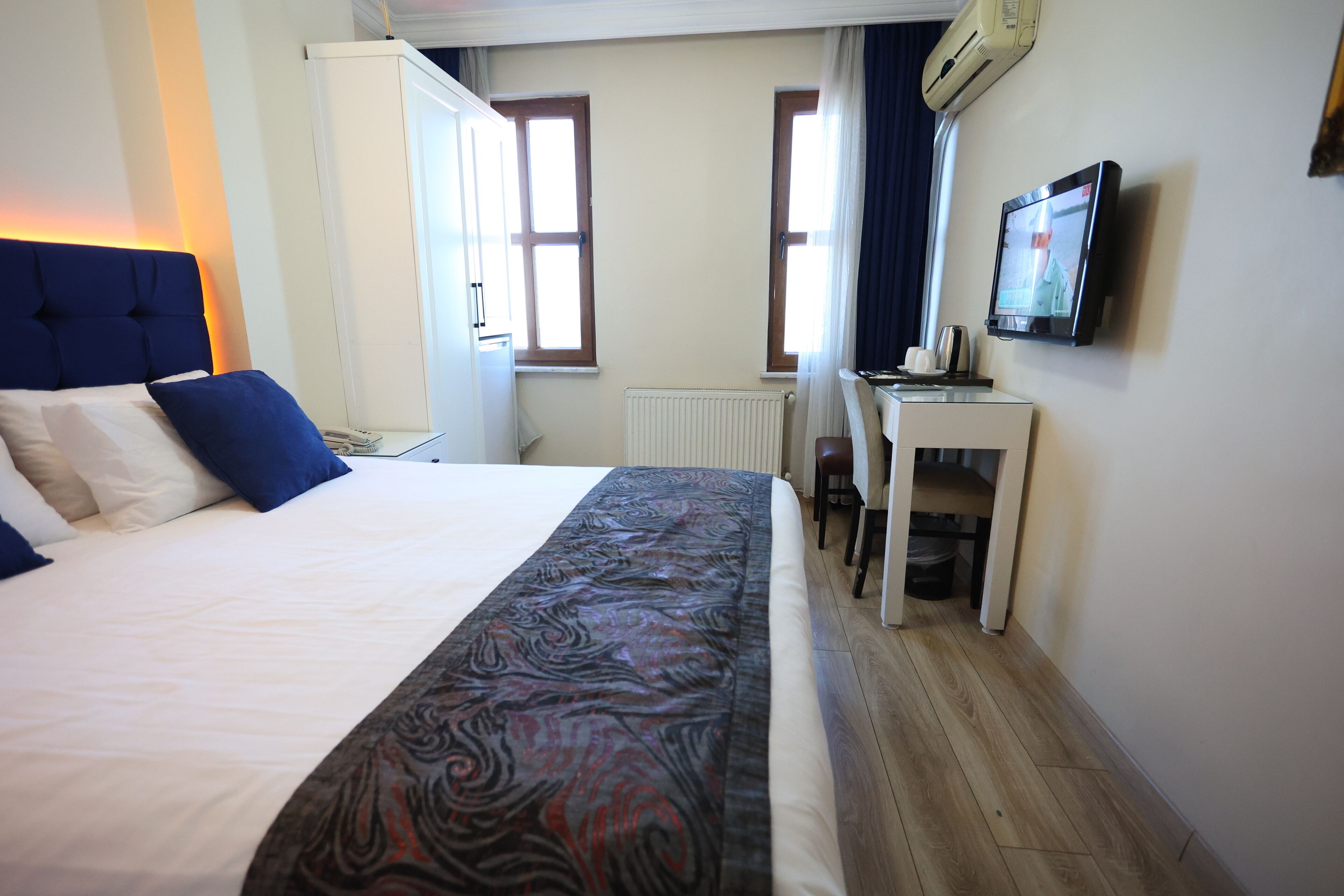 A hotel room with a bed, a desk, a television, and a window.