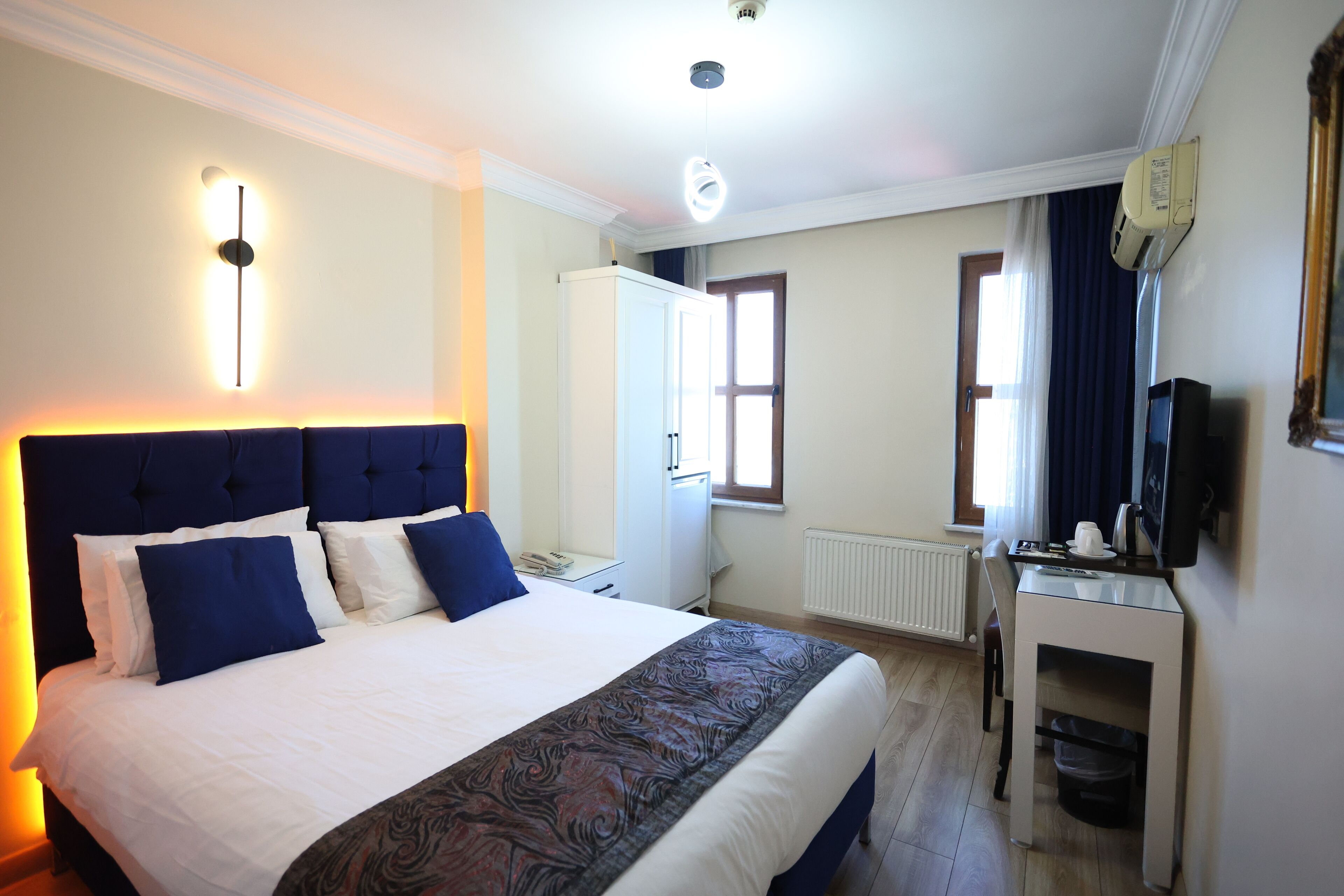 A hotel room with a large bed, a desk, a television, and a wardrobe.