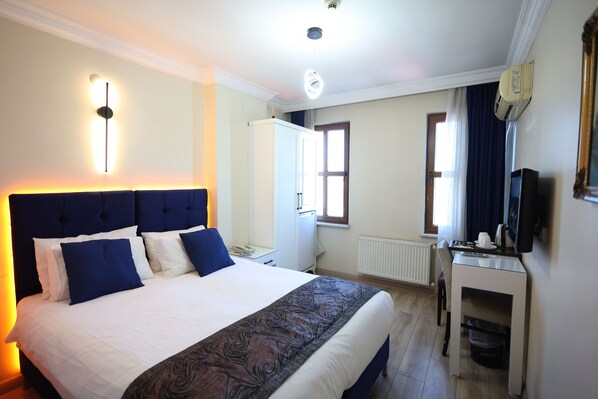 Una habitación de hotel con una cama grande, un escritorio, un televisor y un armario.