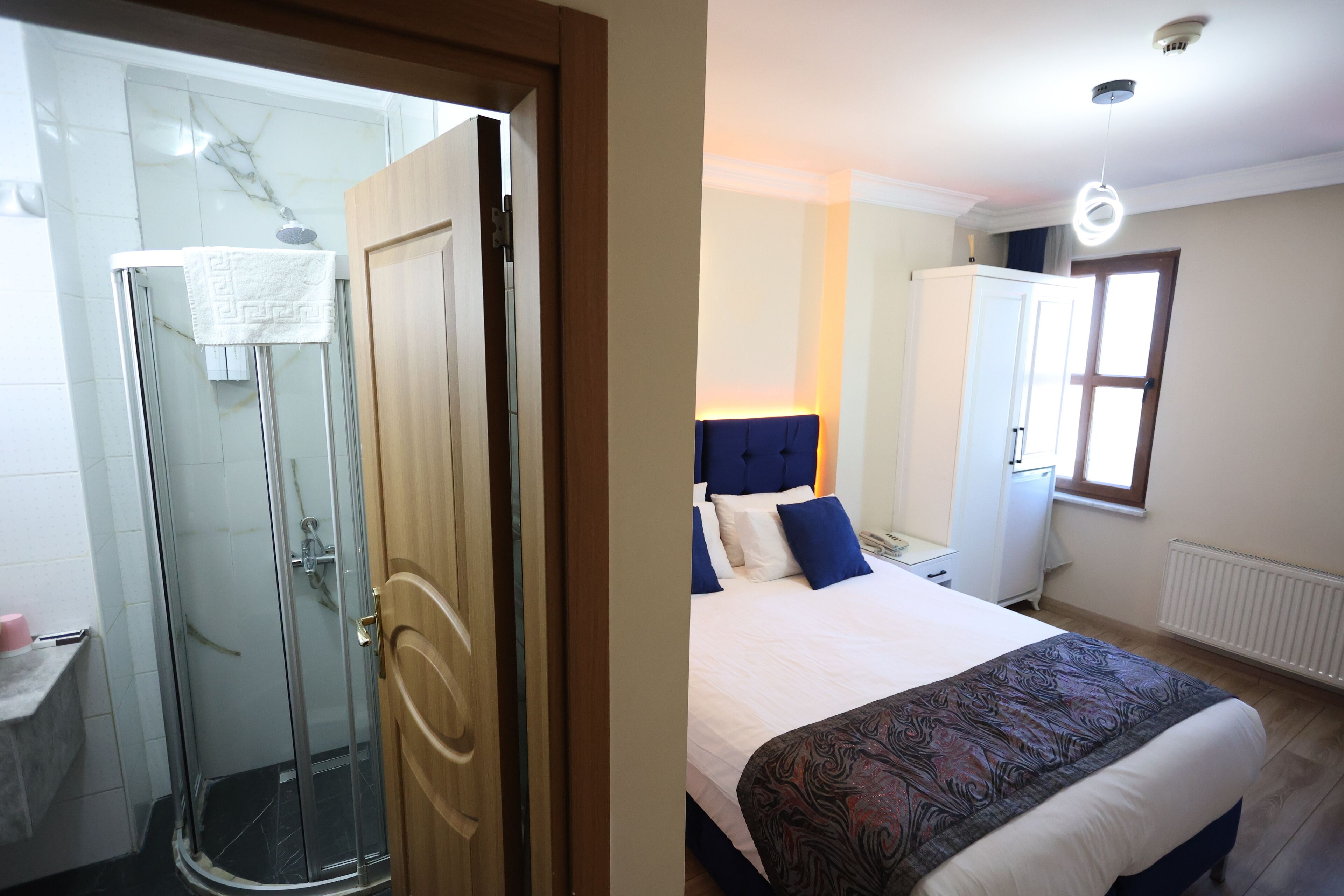 A bedroom with a bed, a nightstand, a wardrobe, and a window.