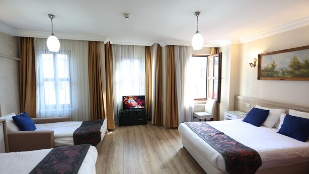 Habitación de hotel con dos camas, televisor, escritorio y una silla.