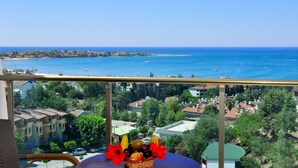 A balcony with a view of the sea, a table with fruit and flowers, and residential buildings in the background. - Side Prenses Resort Hotel & Spa - All Inclusive (Manavgat)