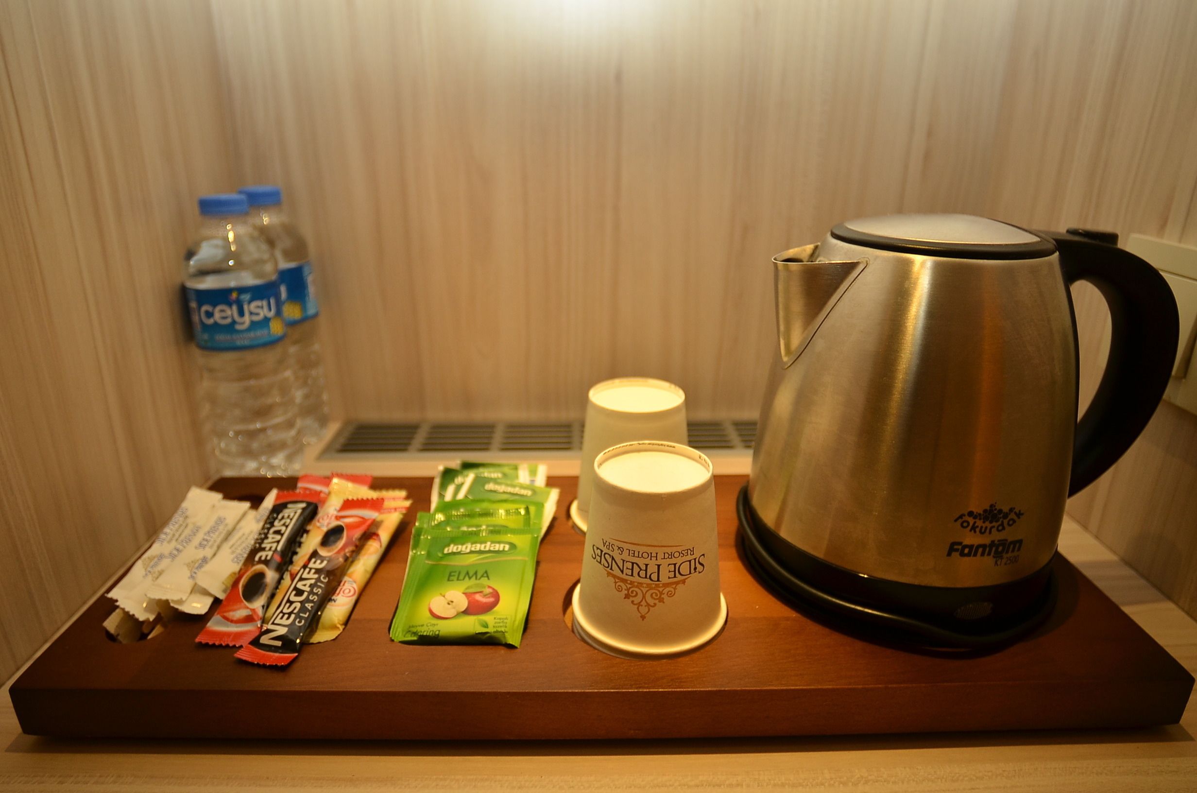 A tray with a water bottle, a coffee maker, two cups, and some snack packets.