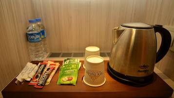 A tray with a water bottle, a coffee maker, two cups, and some snack packets.