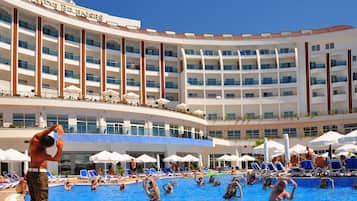 Un hotel con varios balcones, piscina y tumbonas.