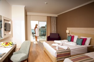Habitación de hotel con cama, una silla, un escritorio con frutero y vistas al exterior.