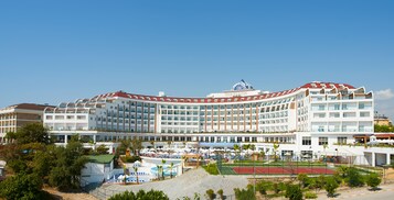 Un hotel grande de varios pisos con una fachada curva, una cúpula central y una terraza en la azotea.
