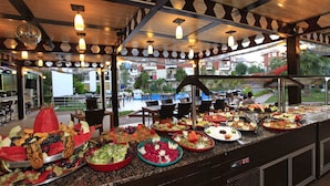 Un buffet proposant divers plats, avec vue sur l’espace extérieur aménagé pour les repas.