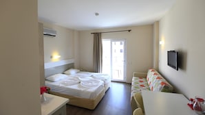Une chambre d’hôtel avec un lit, un bureau, une chaise, une télévision et une fenêtre avec des rideaux.