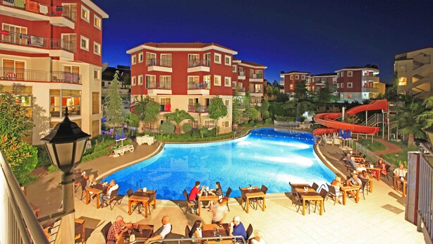 Une piscine entourée d’espaces de détente en plein air et d’immeubles à plusieurs étages dotés de balcons.