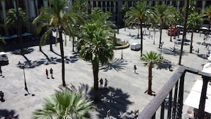 Una amplia plaza pública con palmeras y un edificio al fondo.