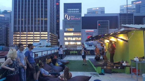 A rooftop bar with a stage for live music, surrounded by seating areas and city views. - PODs The Backpackers Home & Cafe (Kuala Lumpur)