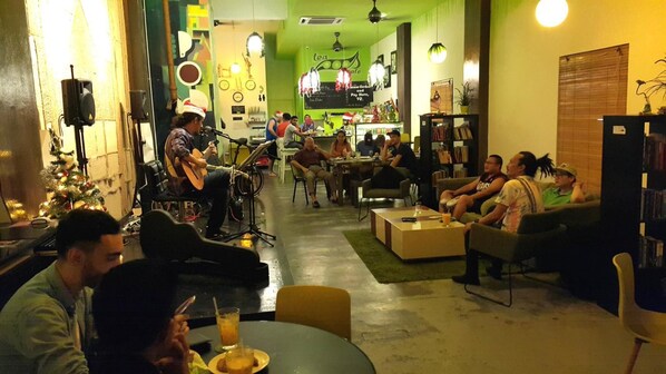 A cozy indoor space with a stage for live performances, seating areas, and a bar.