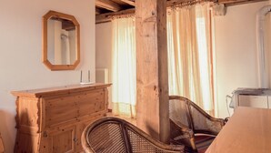 Une pièce comprenant une commode en bois, des chaises en osier, une table en bois et un grand miroir accroché au mur.