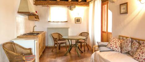 A compact room with a kitchenette, a dining area, and a bed.