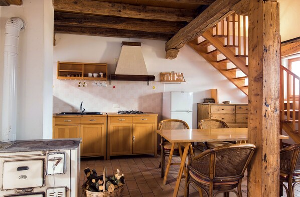 Una cocina rústica con armarios de madera, una estufa y una mesa de comedor con sillas.