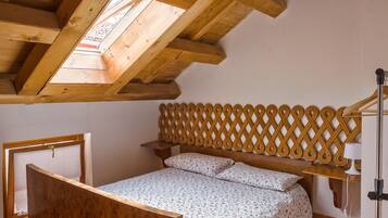 Ein Schlafzimmer mit Holzboden, einem Bett mit floralem Überwurf, einem hölzernen Kopfteil und einem Nachttisch.
