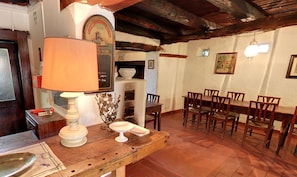Un comedor rústico con una mesa y sillas de madera, un medidor antiguo y una lámpara sobre una mesa de madera.