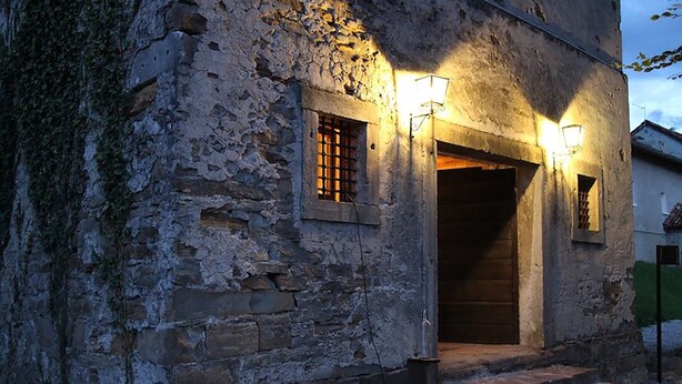 Un bâtiment en pierre avec une porte en bois et deux fenêtres illuminées.
