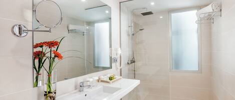 Un baño moderno con un espejo grande, un lavabo, una ducha y zona de ducha con mampara de vidrio.