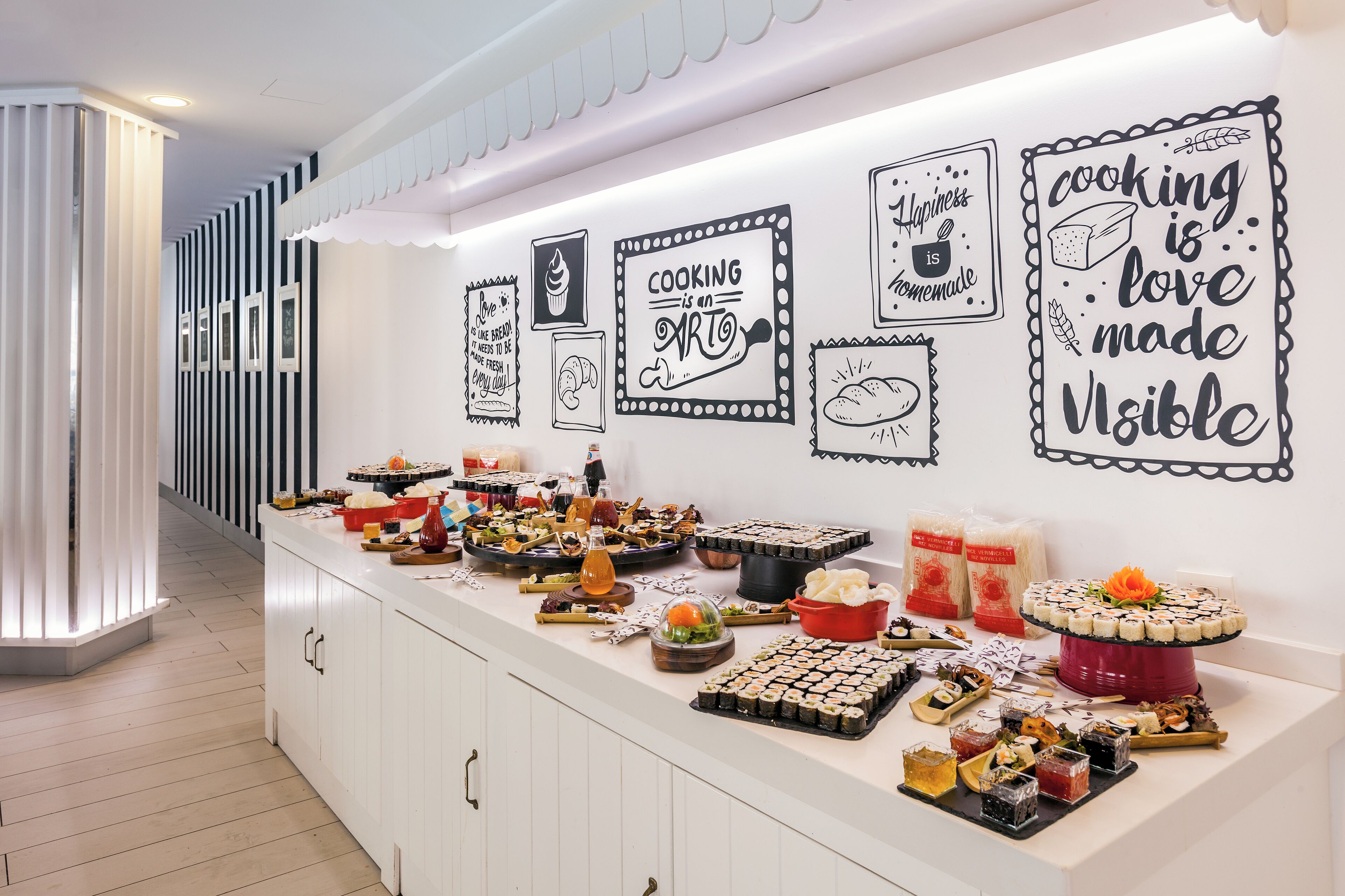 A kitchen area with a long counter displaying various food items and cooking-themed decorations.