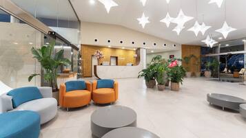 A modern hotel lobby with a reception desk, seating area, and decorative star-shaped lights.