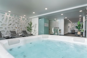 A spa area with a hot tub, lounge chairs, and a wall with a unique cut-out design.