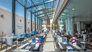 Un restaurant modern amb parets de vidre, caires blaus i grisos, i taules preparades per dinar.