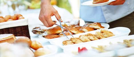 A buffet with various food items and a person serving themselves.