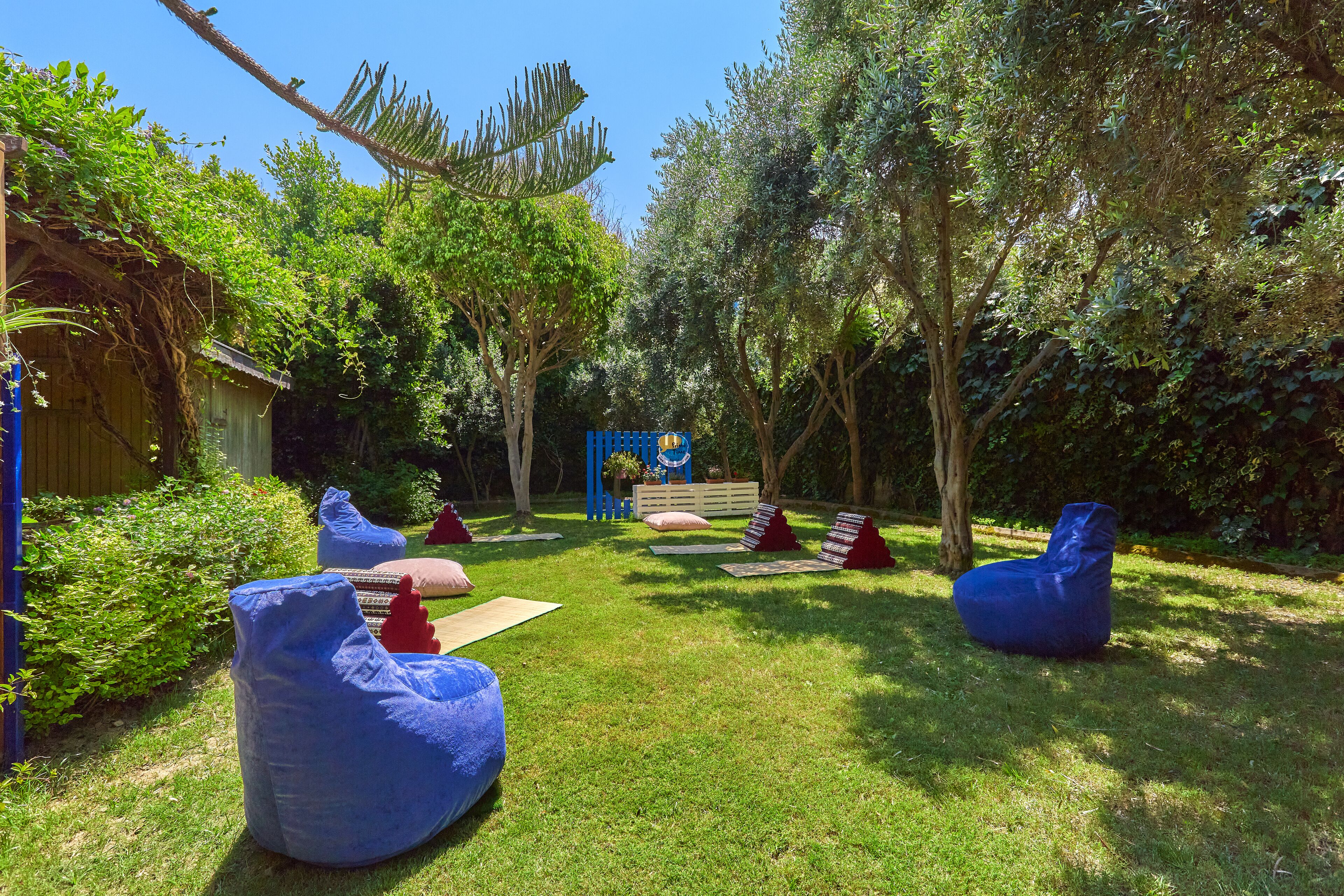 Un jardín con sillones orejeros azules y una hamaca.