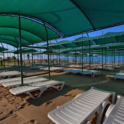 Aan een privéstrand, ligstoelen, parasols, beachvolleybal