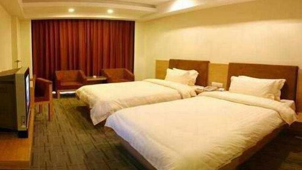 Una habitación de hotel con dos camas, televisión, escritorio y una silla.