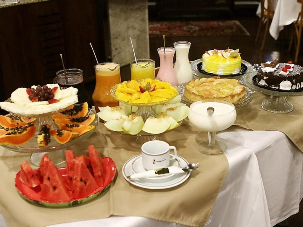 A buffet with various dishes including fruits, desserts, and beverages.