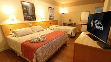 A hotel room with two beds, a TV, and artwork on the walls.