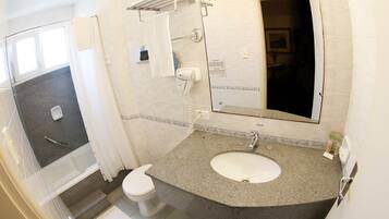 A bathroom with a granite sink, white toilet, and a shower area.