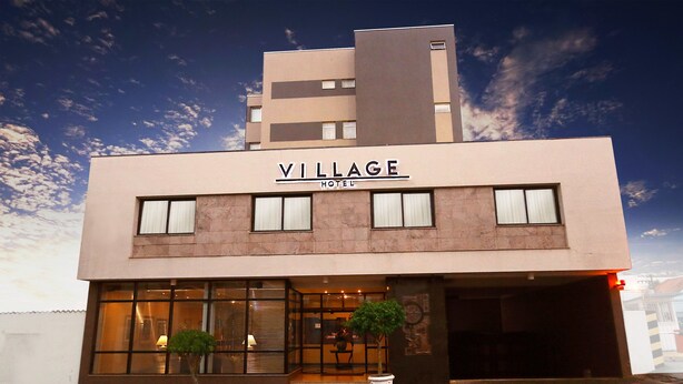 A modern hotel named 'Village Hotel' with a flat roof, large windows, and two potted plants in front. - Village Hotel (Ponta Grossa)
