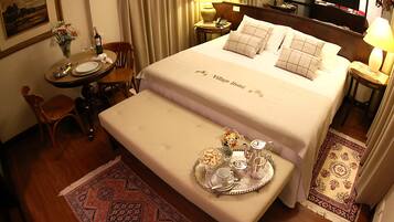 Habitación de hotel con cama, mesitas de noche, una pequeña mesa de comedor, una silla y una bandeja con alimentos para el desayuno.