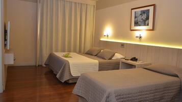 A hotel room with two beds, a bedside table with a phone, and a wall-mounted light fixture.