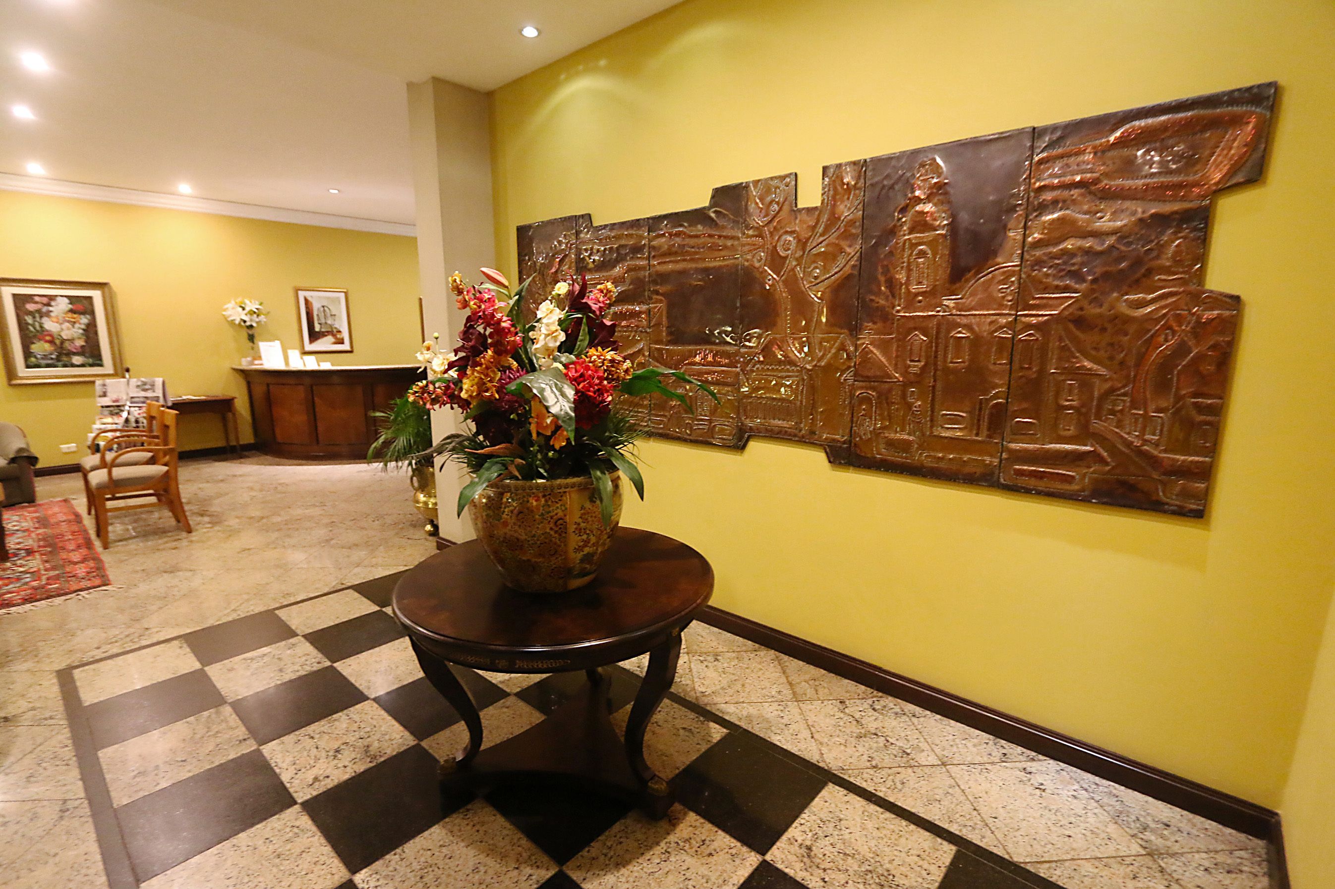 A lobby with a checkered floor, a reception desk, and a large wall art piece.