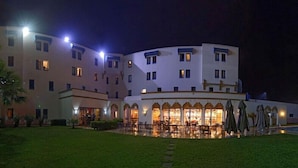 A multi-story hotel with a central courtyard, outdoor seating area, and illuminated windows.