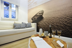 Relax in this serene living room with a sofa, coffee table, and wall mural featuring a peaceful boat scene.