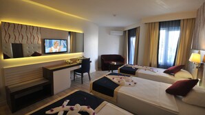 A hotel room with two beds, a desk, a TV, a chair, and a sofa.