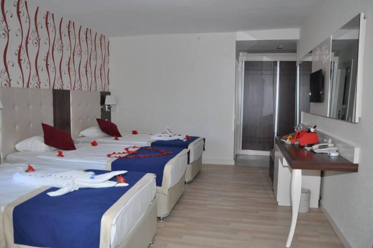 Habitación de hotel con dos camas, un escritorio, un espejo y zona de ducha.