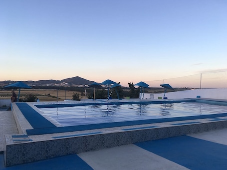 Una piscina al aire libre de temporada, sombrillas