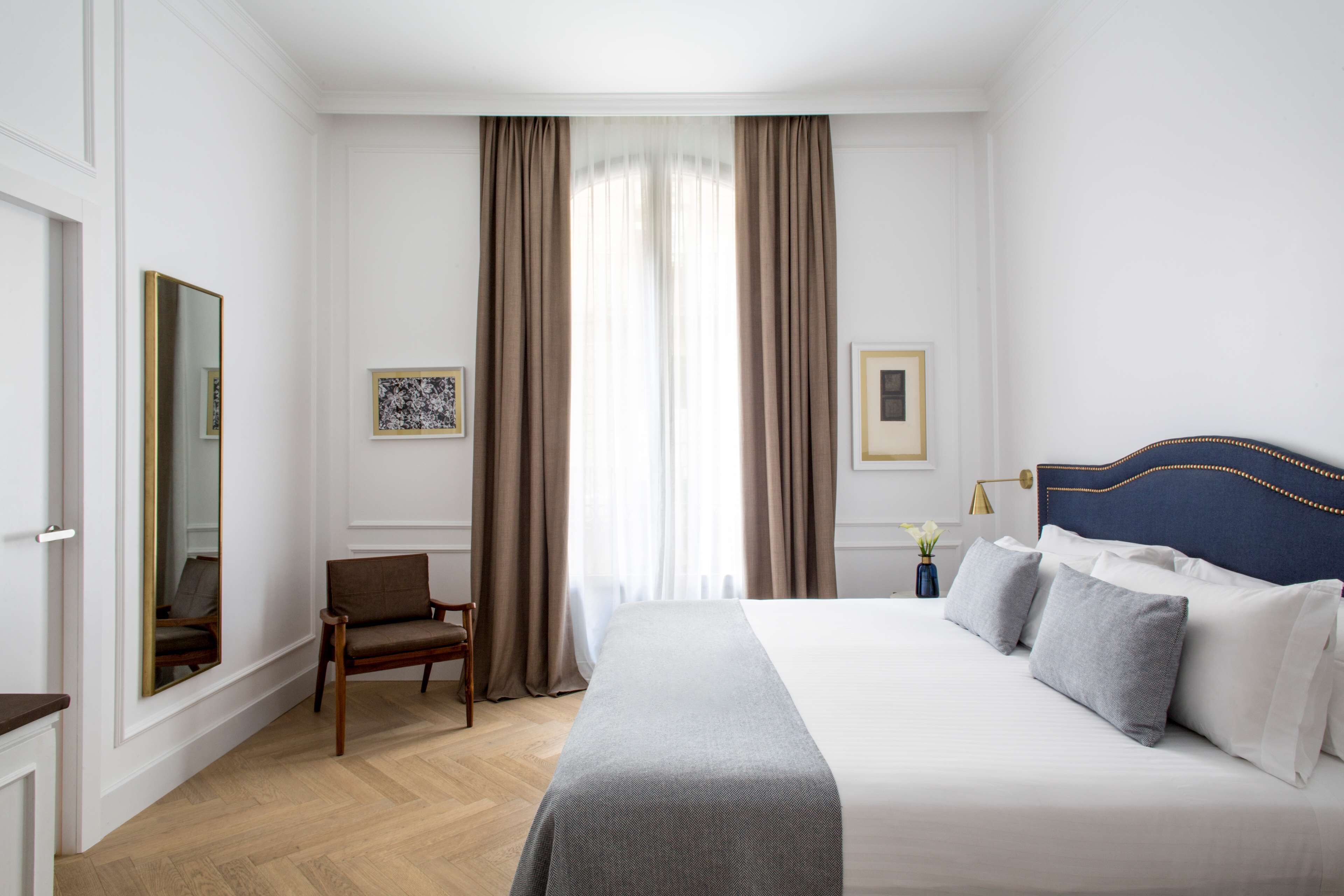 Una habitación de hotel con una cama grande, una silla, un escritorio y un espejo.