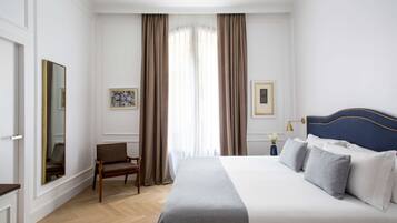 Una habitación de hotel con una cama grande, una silla, un escritorio y un espejo.
