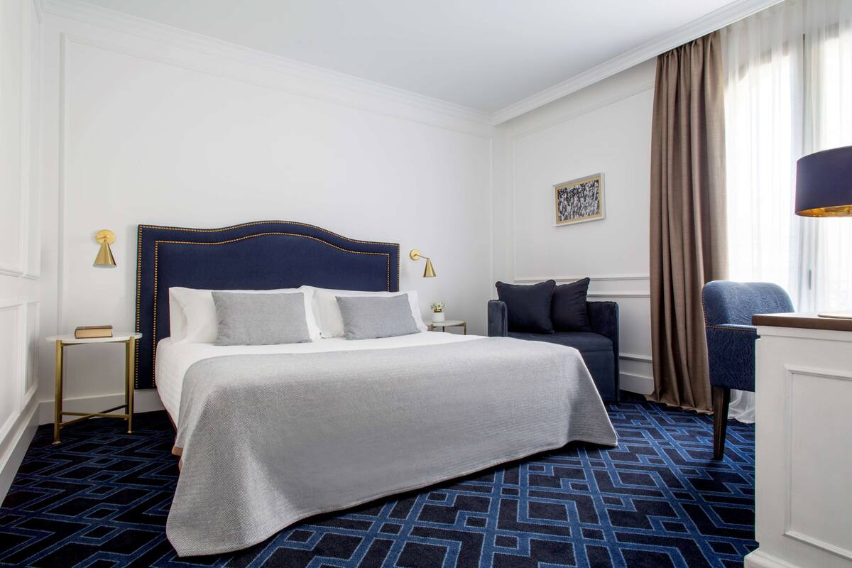 Une chambre d’hôtel avec un grand lit, un bureau, une chaise et une lampe.