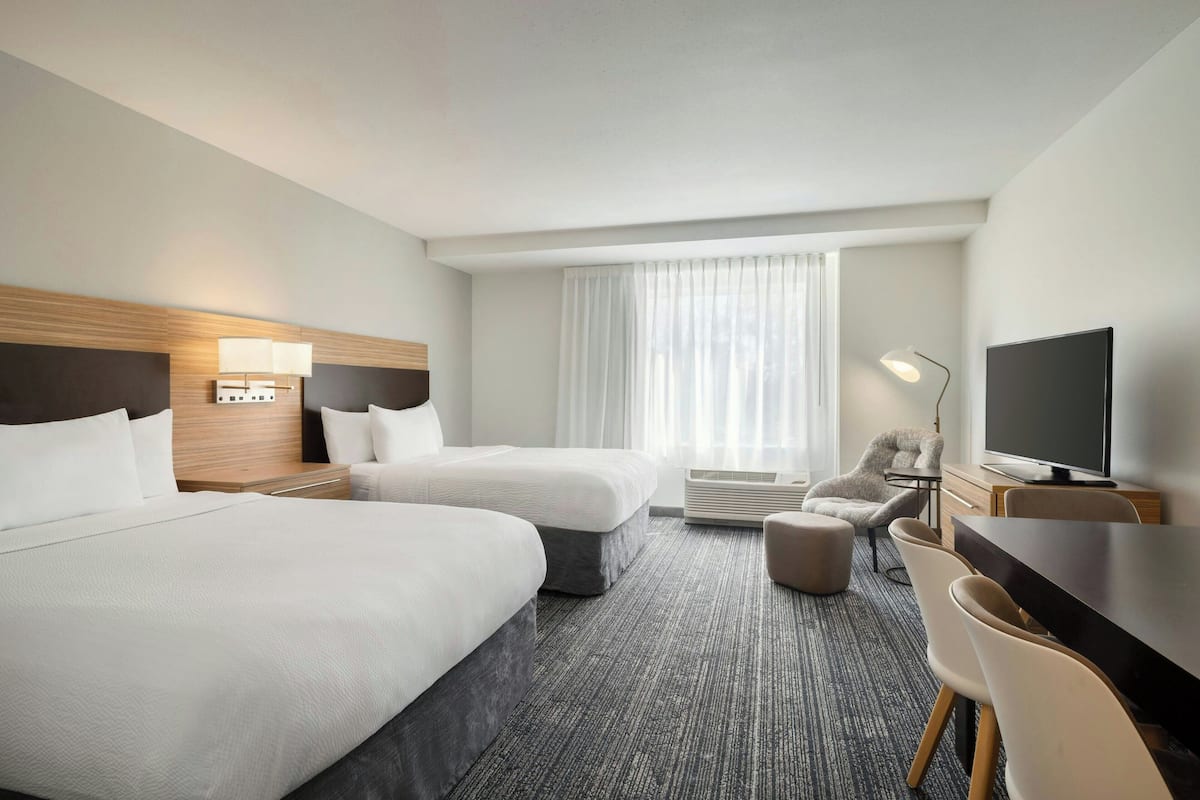 Een hotelkamer met twee bedden, een bureau, een televisie en een stoel.