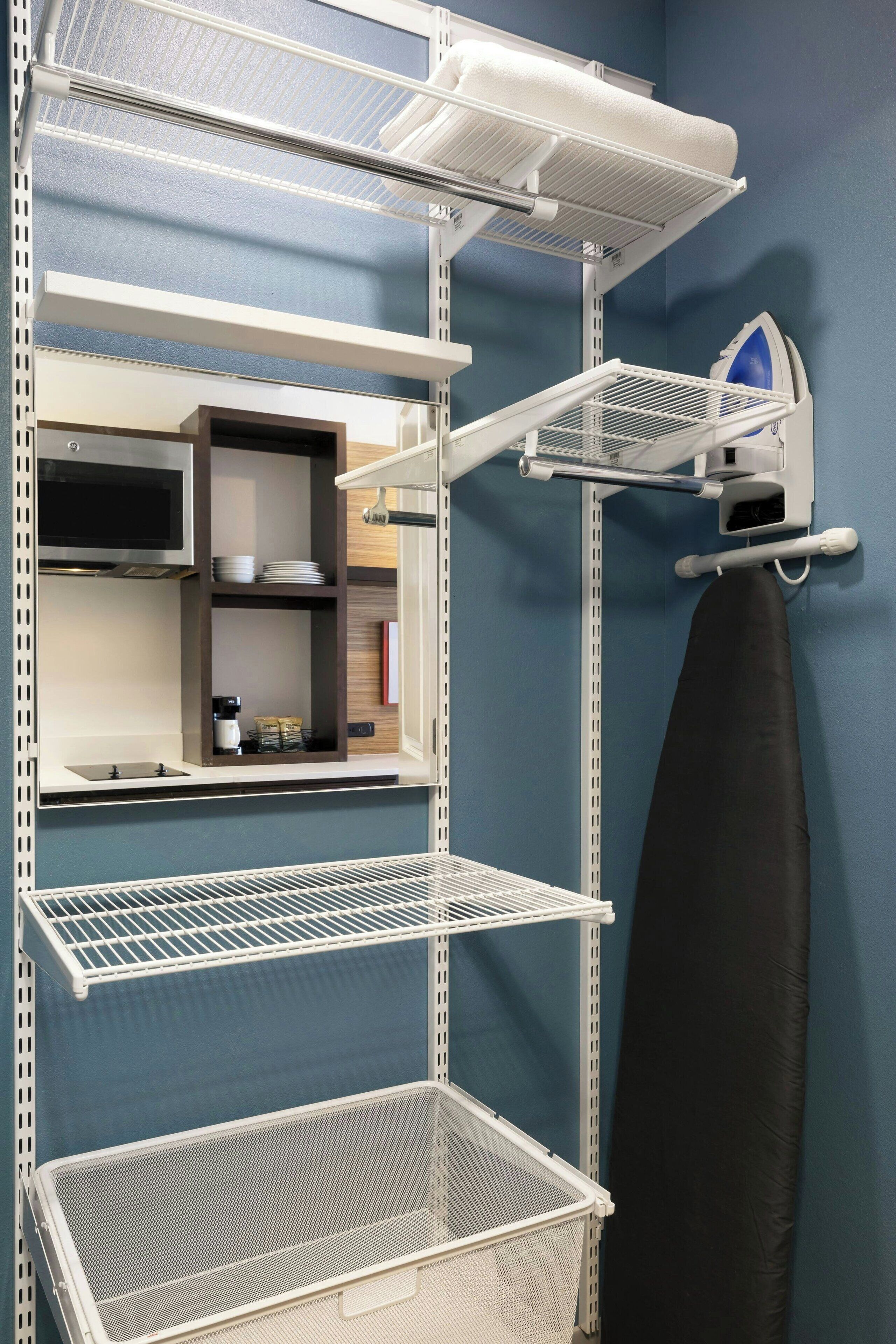 A kitchen with white metal shelves, a microwave, and a coffee maker.