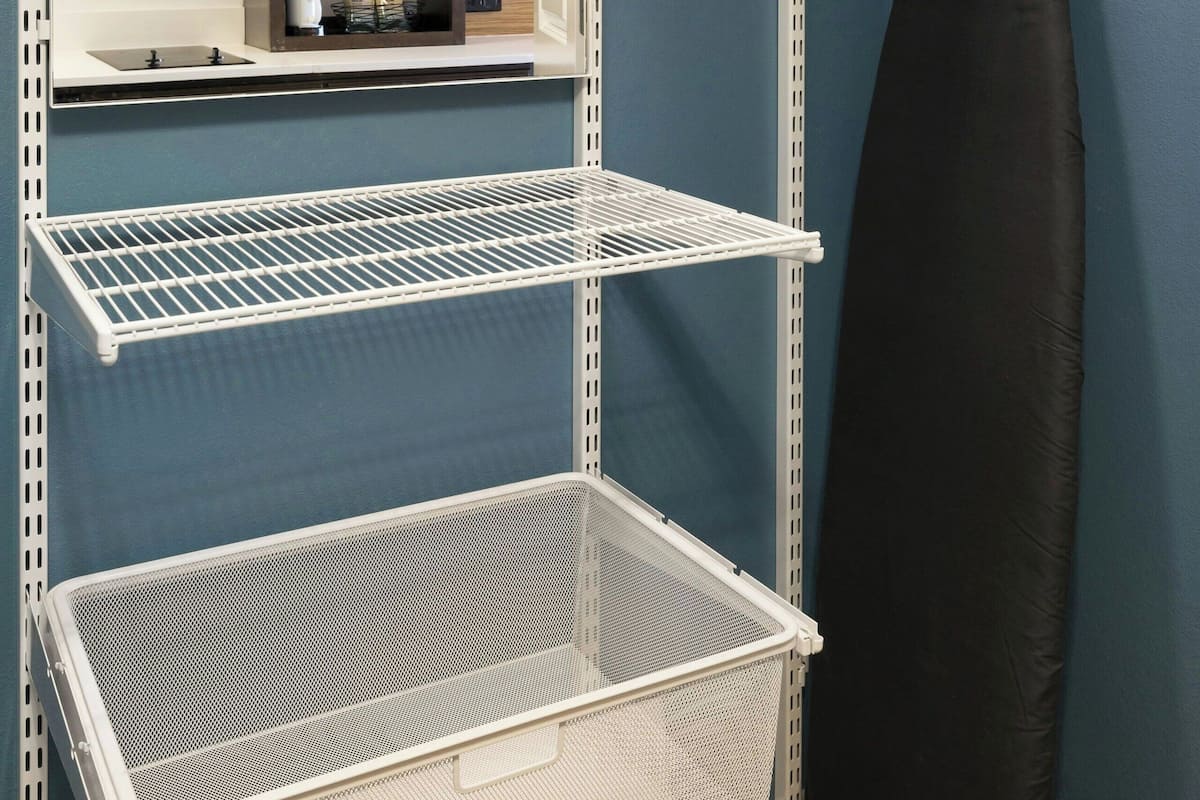 Una cocina con estantes metálicos blancos, un microondas y una cafetera.